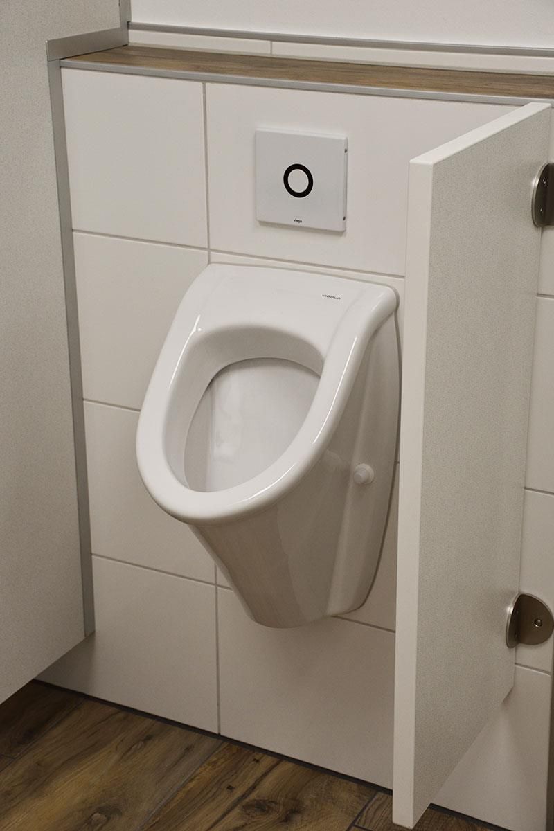 Ein weißes Urinal ist in einem Badezimmer an der Wand montiert