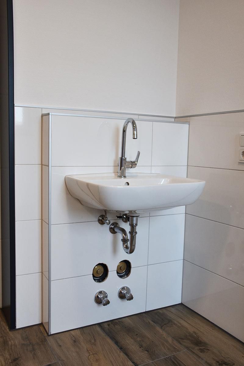 Ein Waschbecken im Badezimmer mit einem Wasserhahn und Rohren darunter