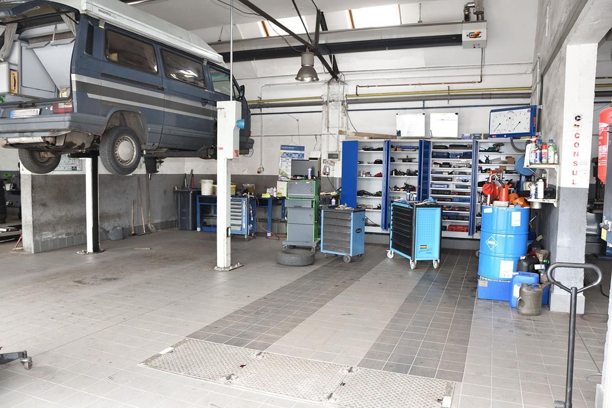 Ein blauer Lieferwagen steht auf einer Hebebühne in einer Garage
