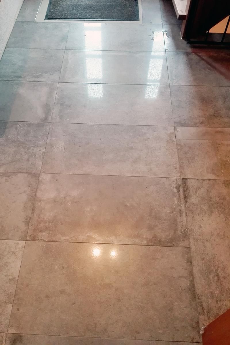 Ein glänzender Fliesenboden in einem Raum mit einem Teppich auf dem Boden.