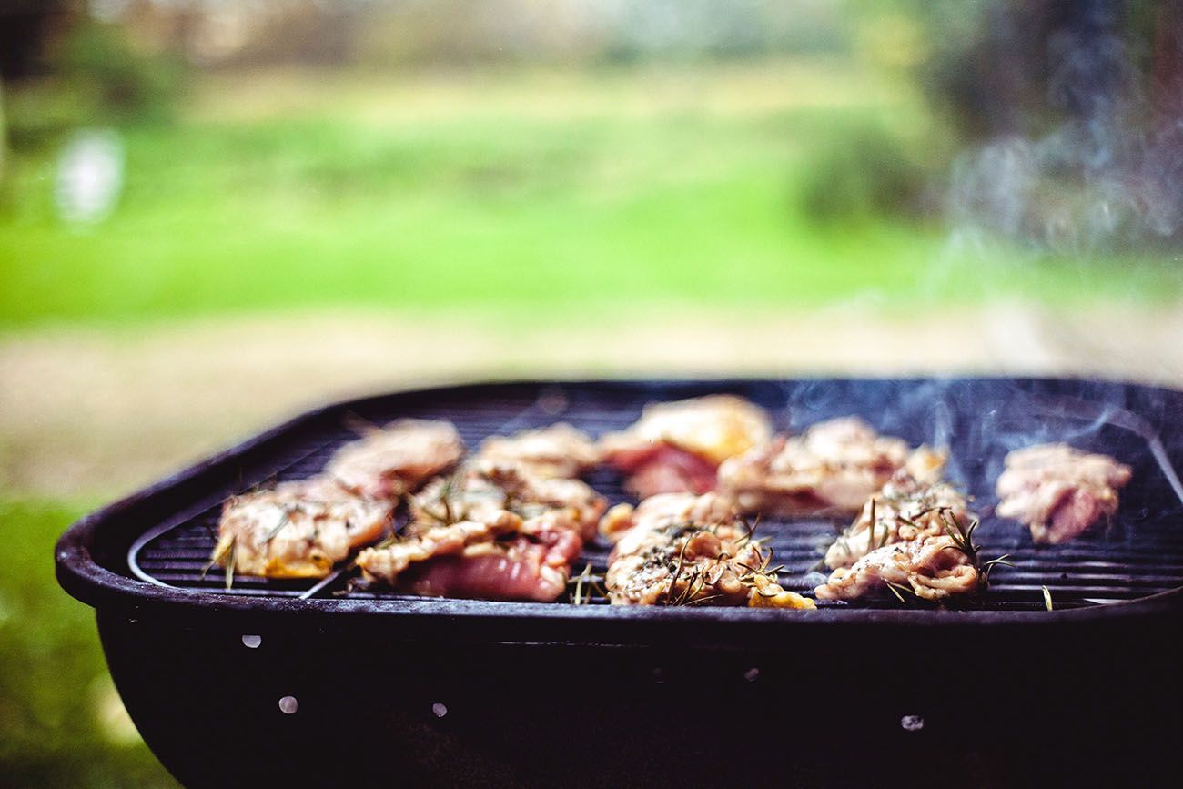 Poulet grillé sur un barbecue rond en extérieur, la fumée s'élevant