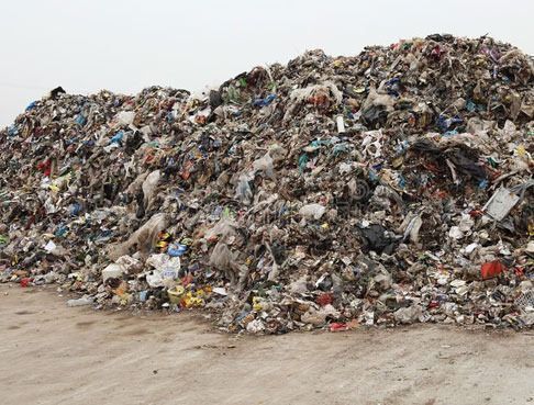 Una gran pila de basura se encuentra encima de un campo de tierra.