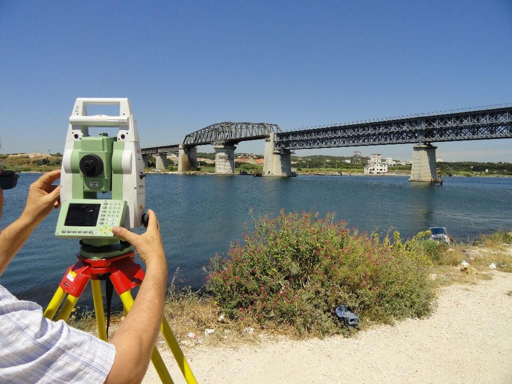 Géomètre utilisant une station totale sur trépied sur un chantier de construction.