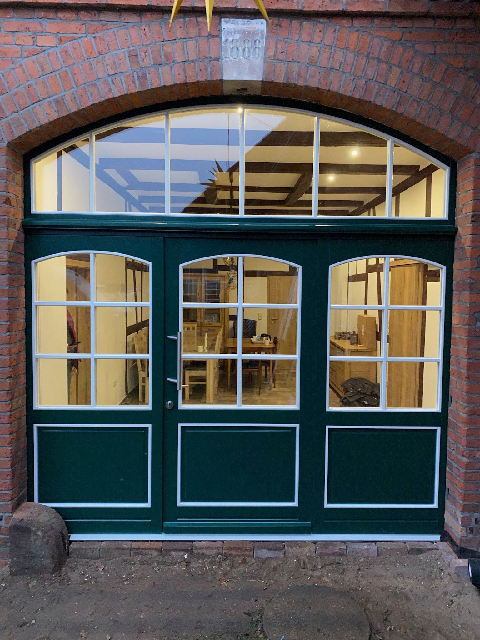 Ein Backsteingebäude mit einer grünen Tür und vielen Fenstern