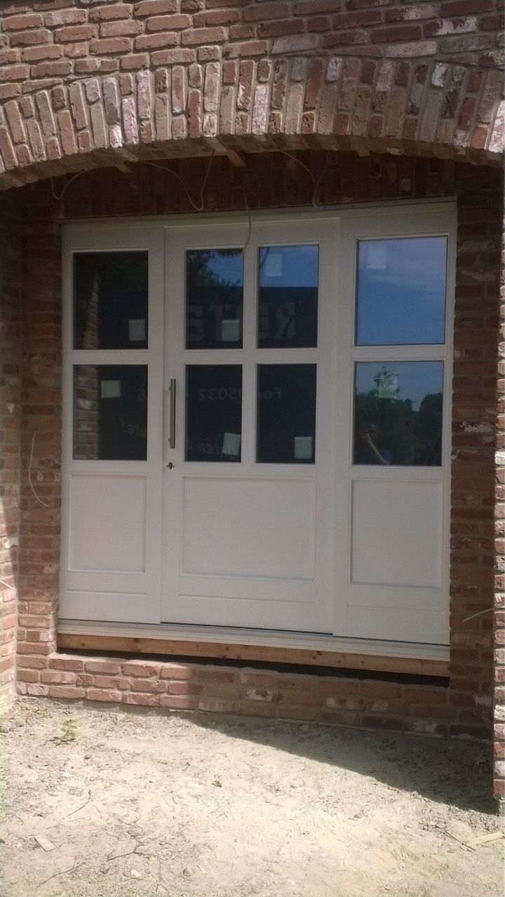 Vor einem Backsteingebäude steht eine weiße Tür.