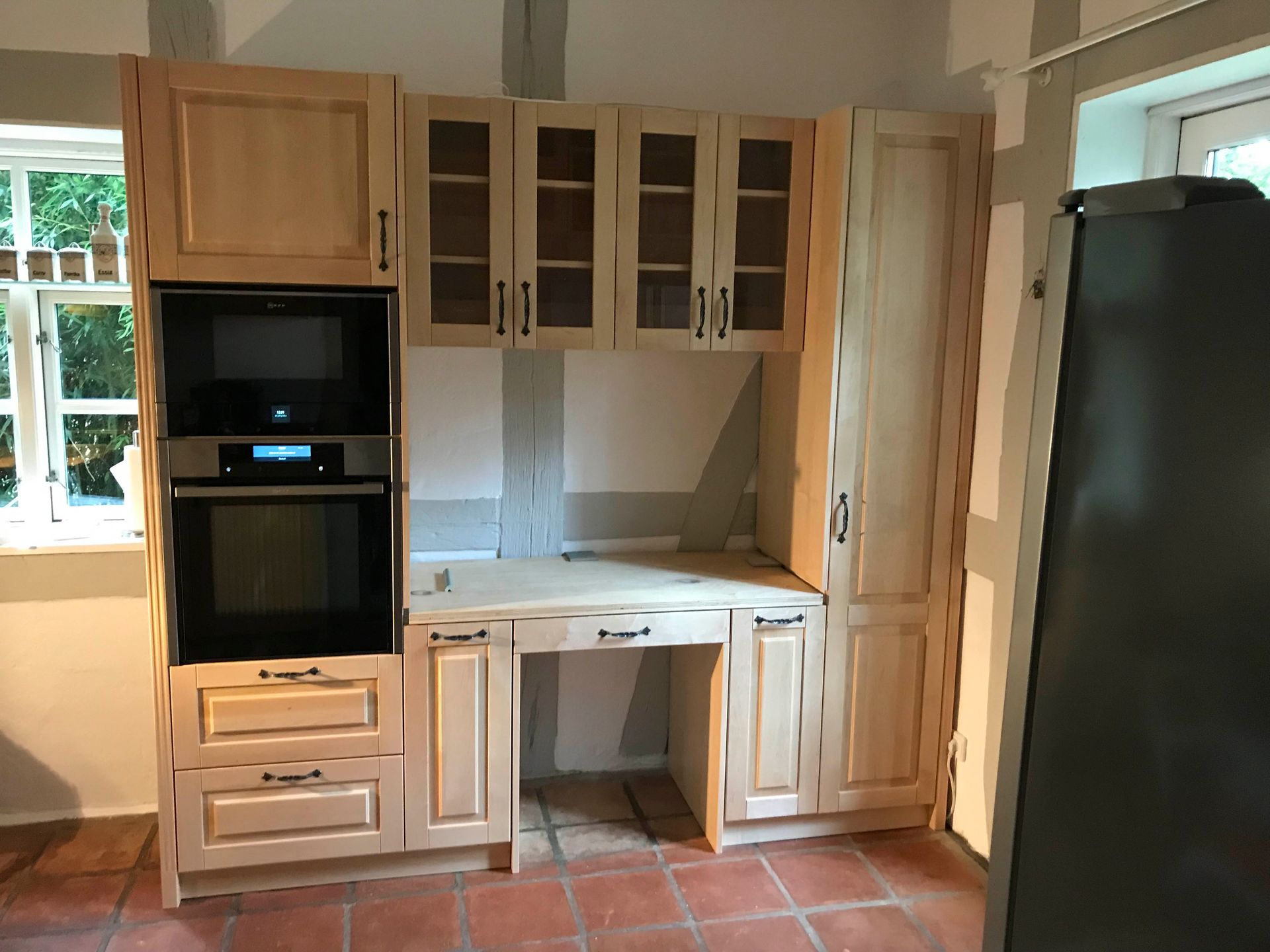 Eine Küche mit Holzschränken und einem schwarzen Kühlschrank