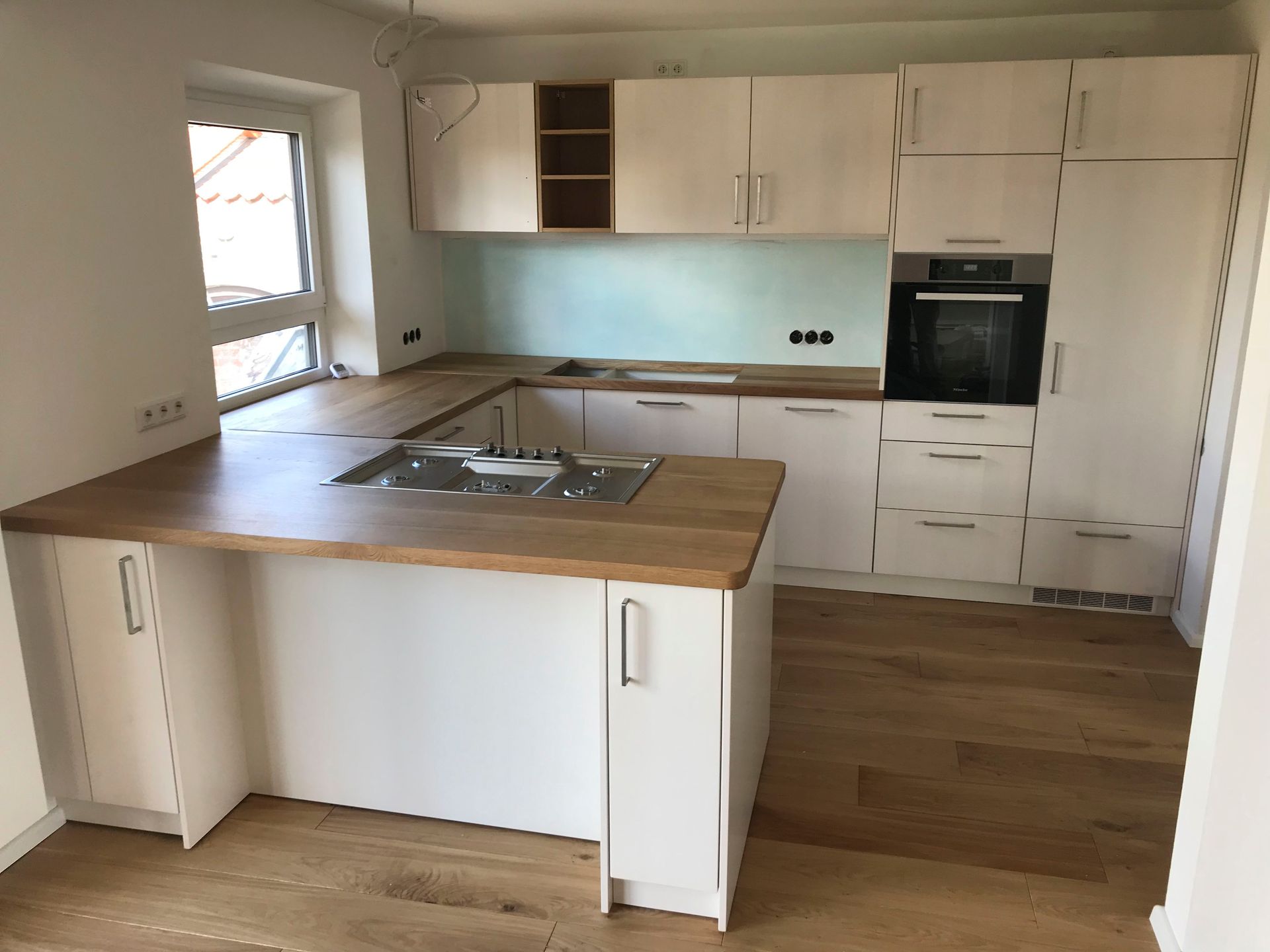 Eine Küche mit weißen Schränken und Holzarbeitsplatten