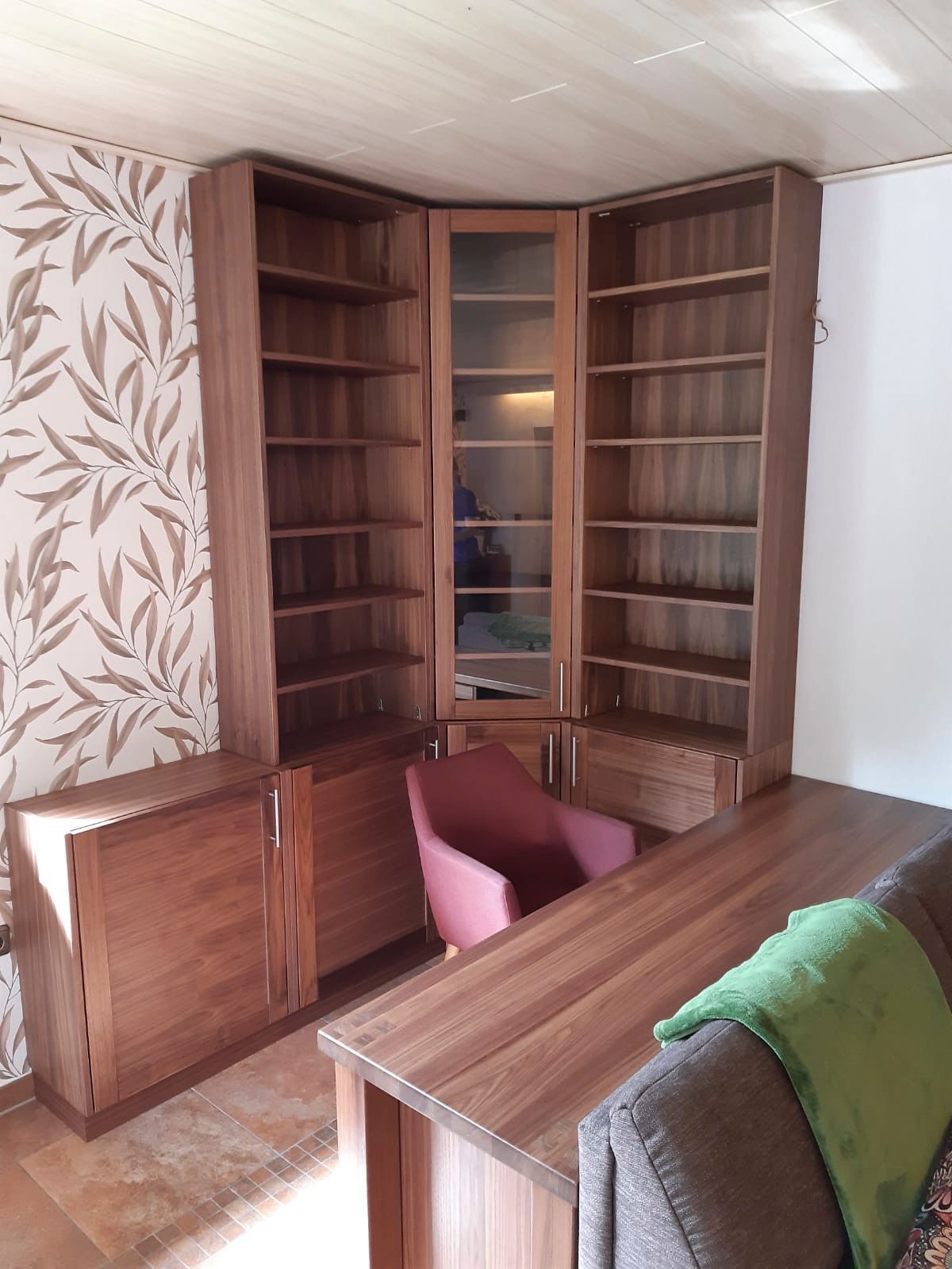 Ein Wohnzimmer mit Couch, Schreibtisch, Sessel und Regalen.