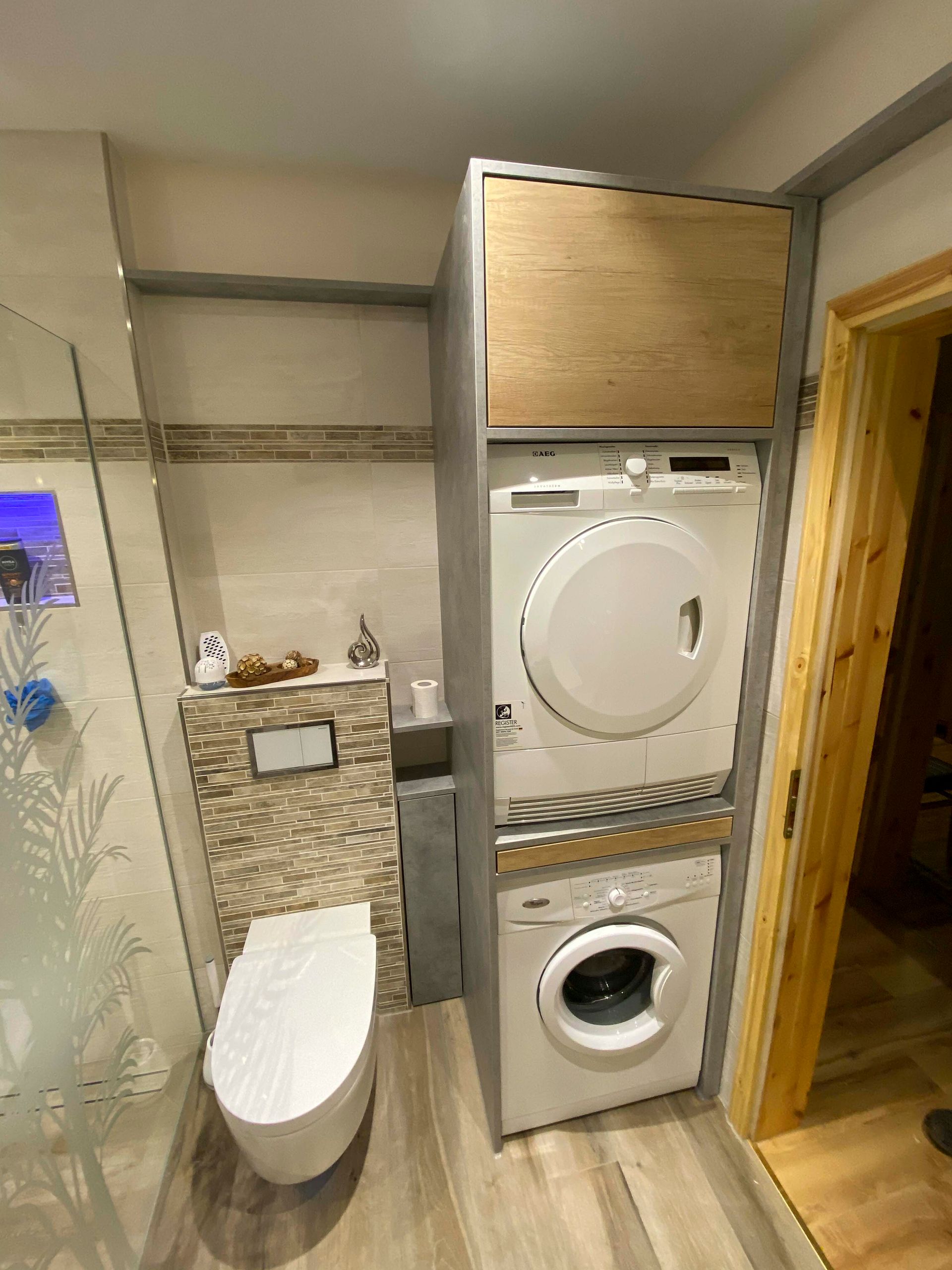 Ein Badezimmer mit Toilette, Waschmaschine und Trockner übereinander gestapelt.