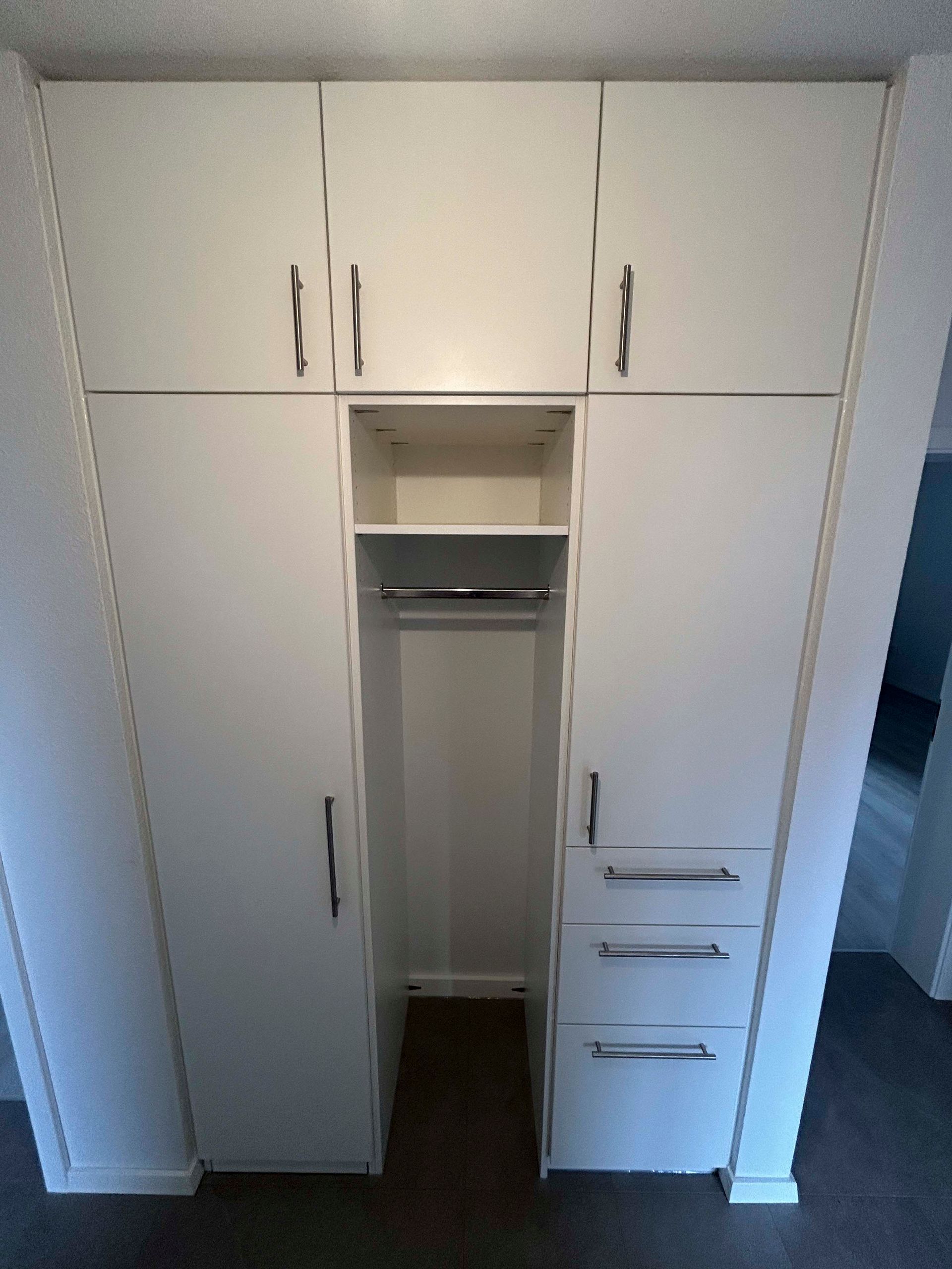 Ein Schrank mit vielen weißen Schränken und Schubladen