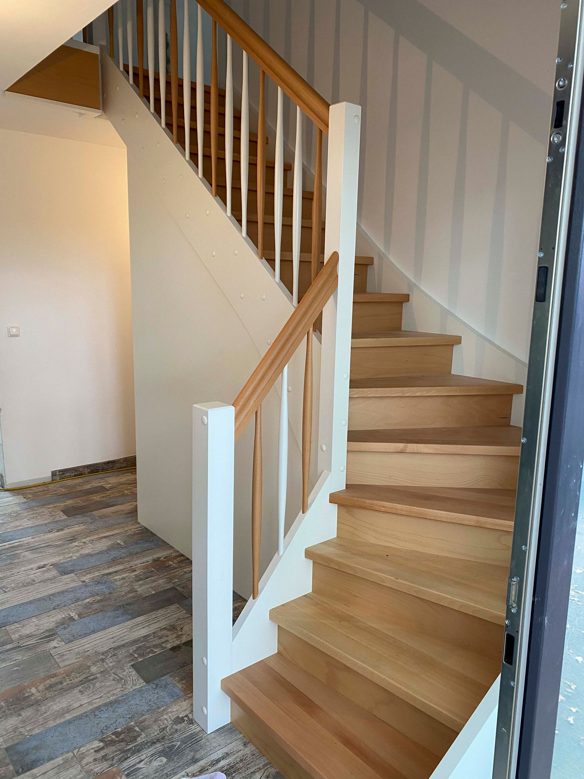 Eine Holztreppe mit einem weißen Geländer in einem Haus.