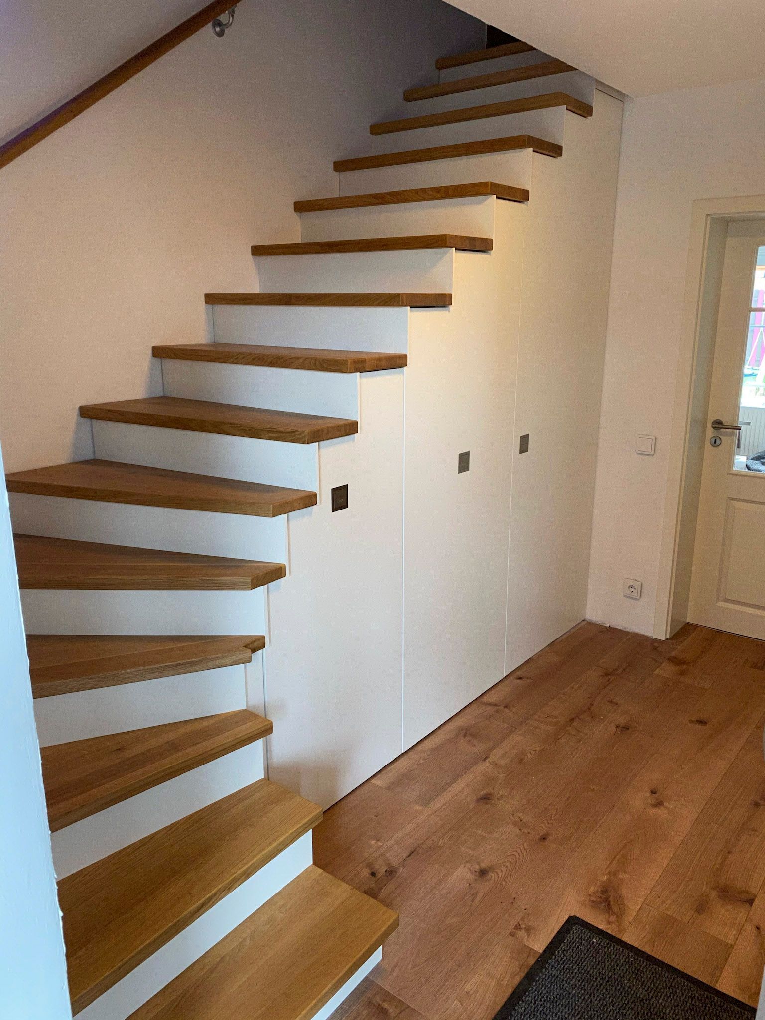 Eine Treppe mit Holzstufen und weißen Stufen in einem Flur.