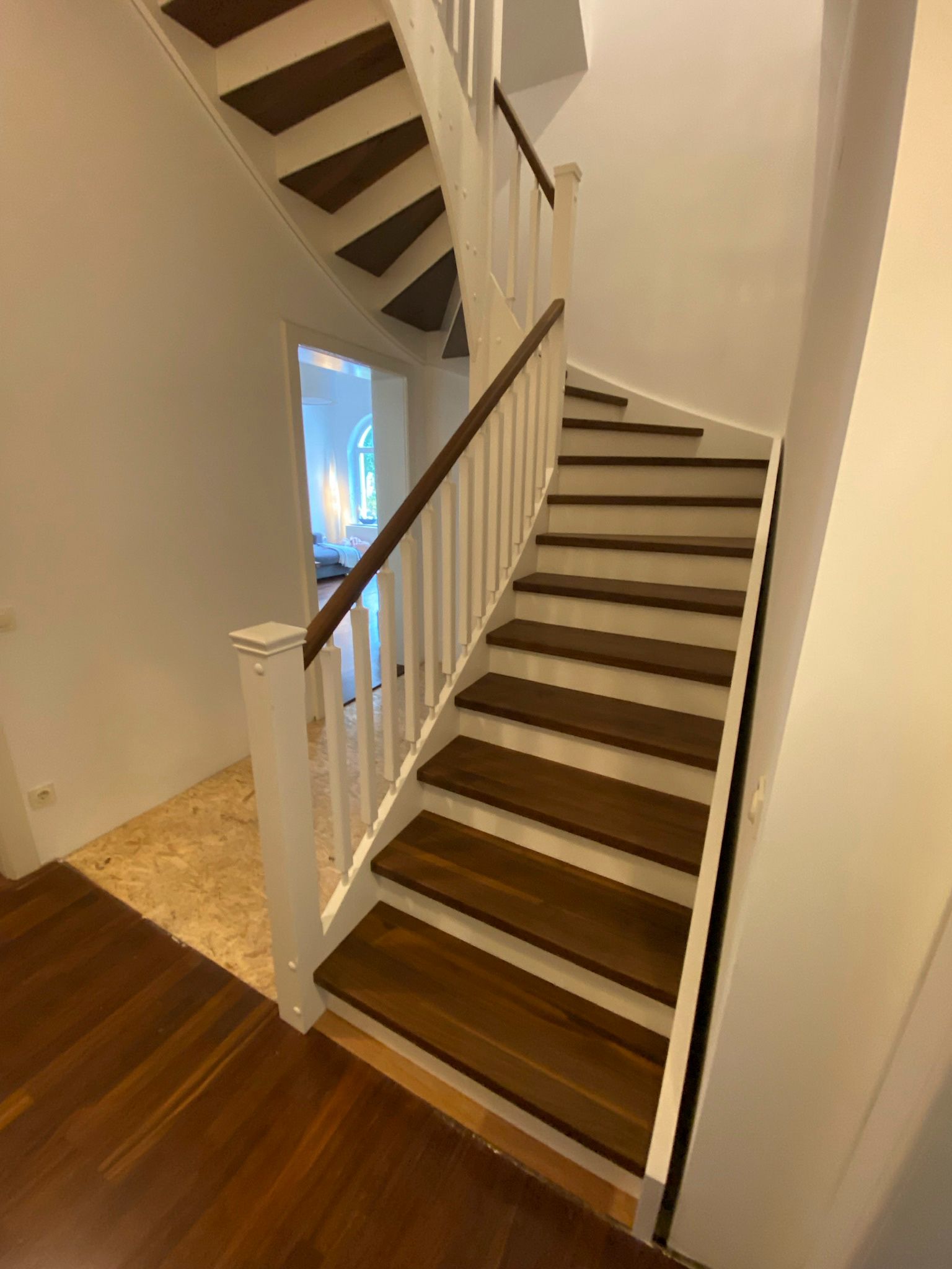 Eine Treppe mit Holzstufen und einem weißen Geländer in einem Haus.