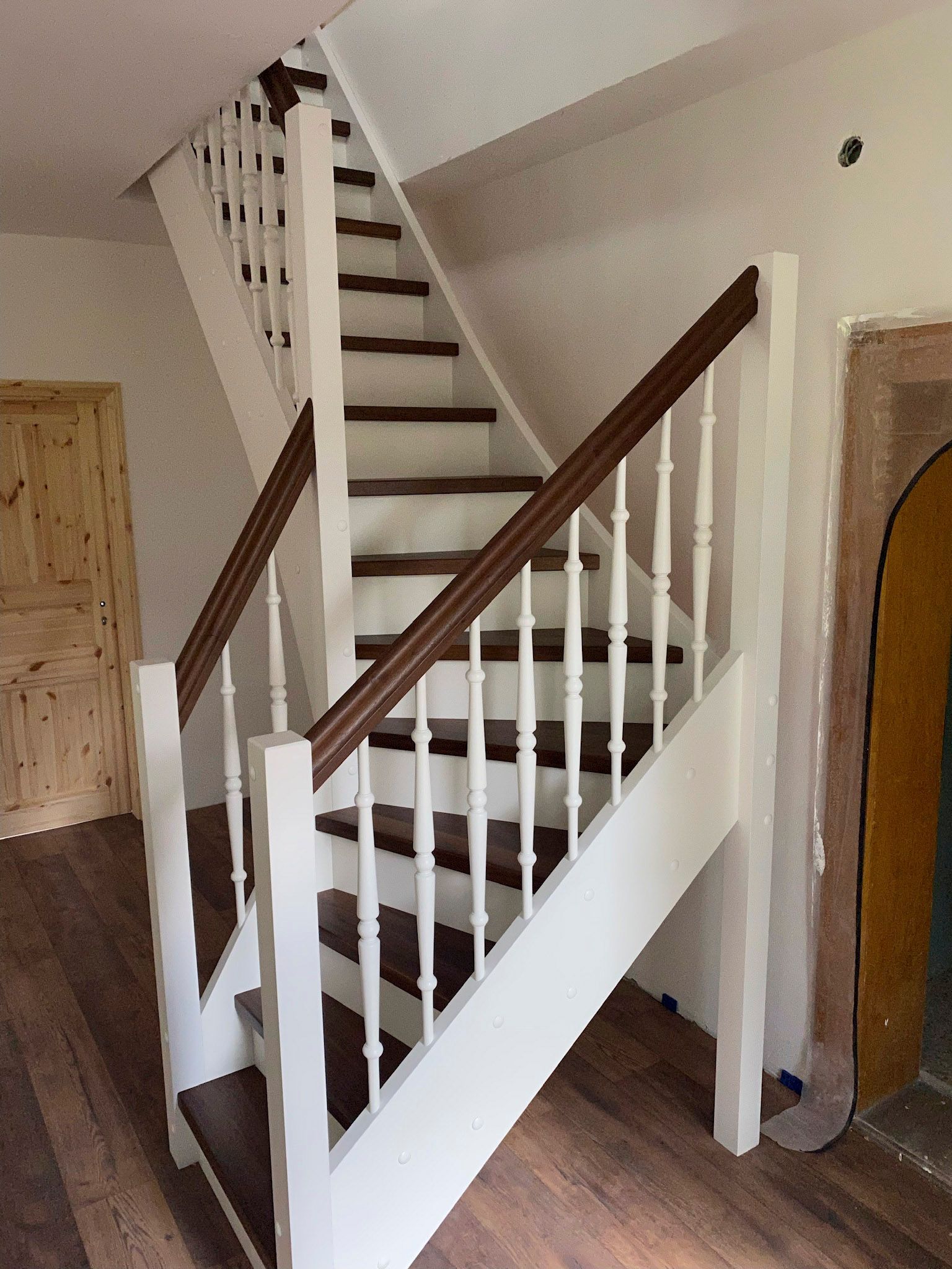 Eine weiße Treppe mit Holzstufen und Holzgeländer