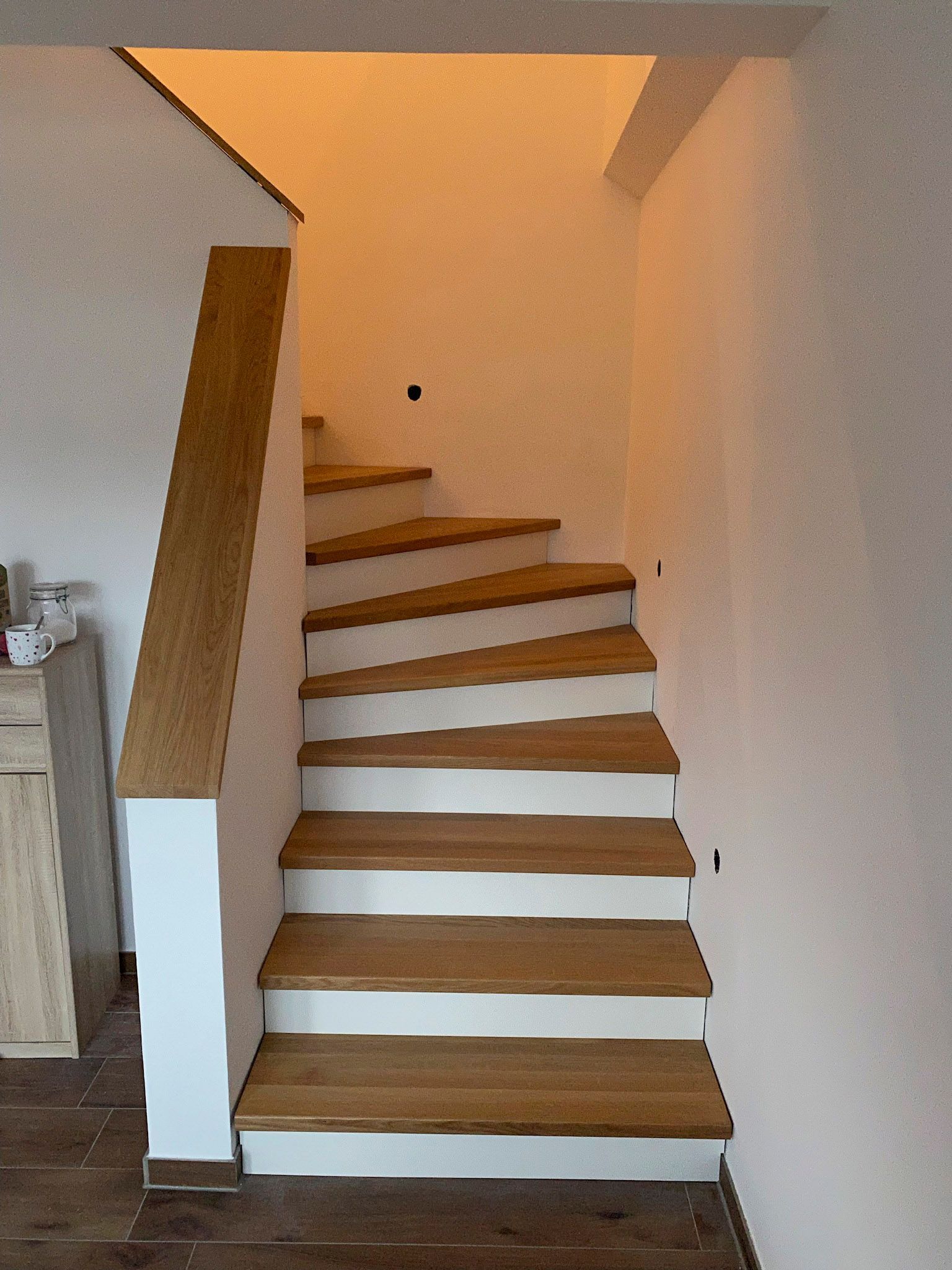 Eine Holztreppe mit weißen Stufen und einem Holzgeländer