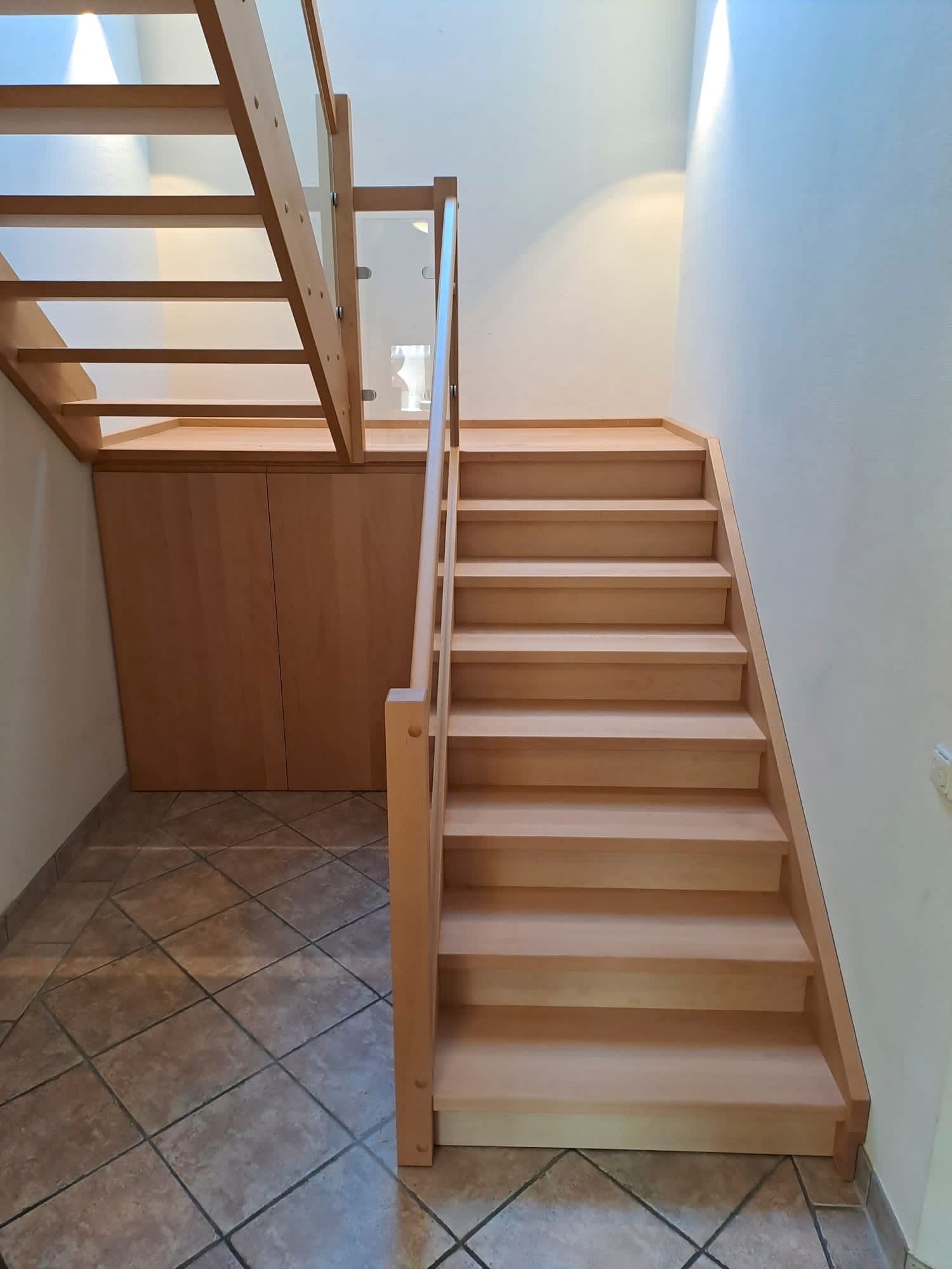 Eine Holztreppe mit Glasgeländer in einem Flur