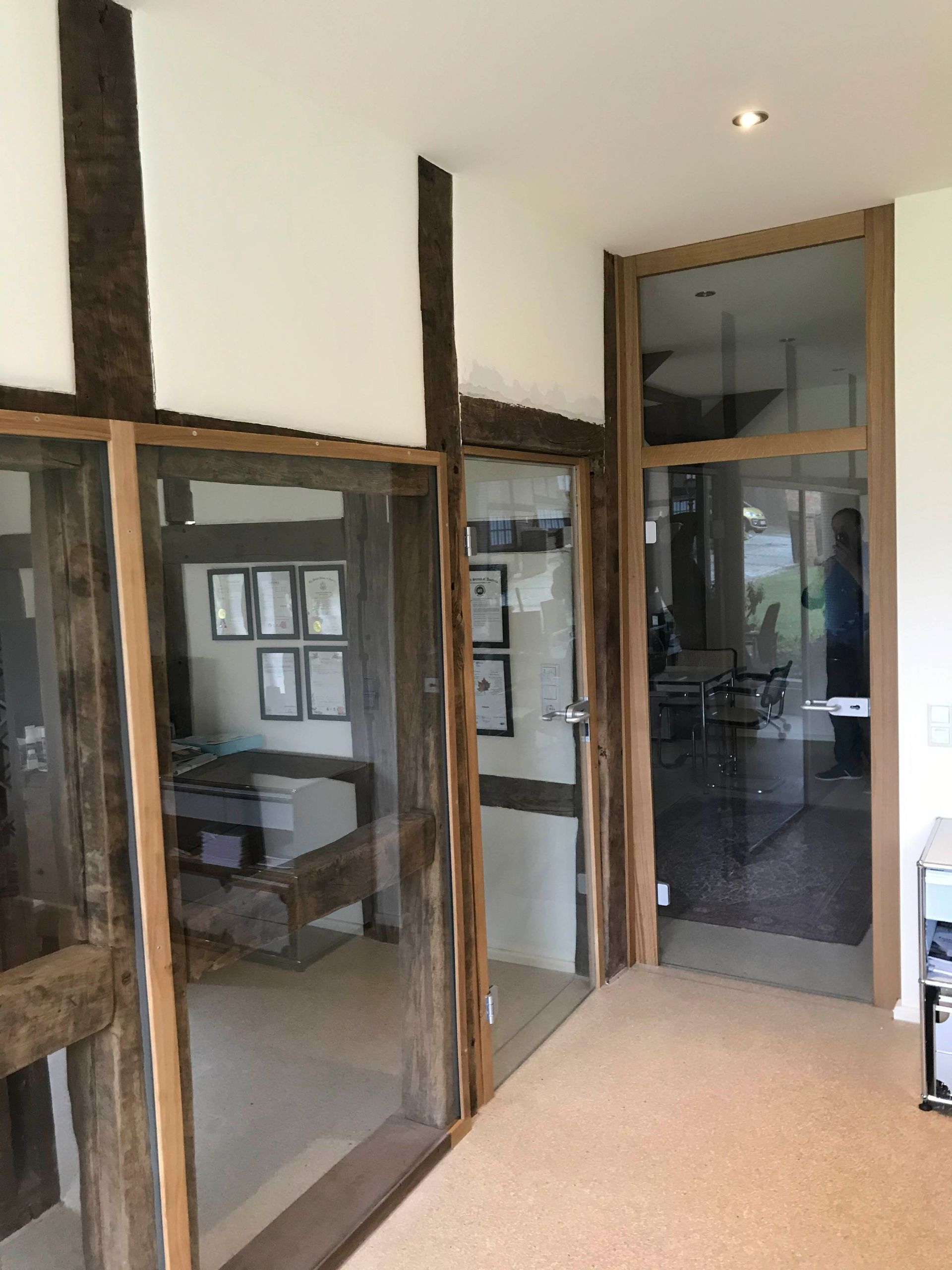 Ein Flur mit vielen Glastüren und Holzbalken.
