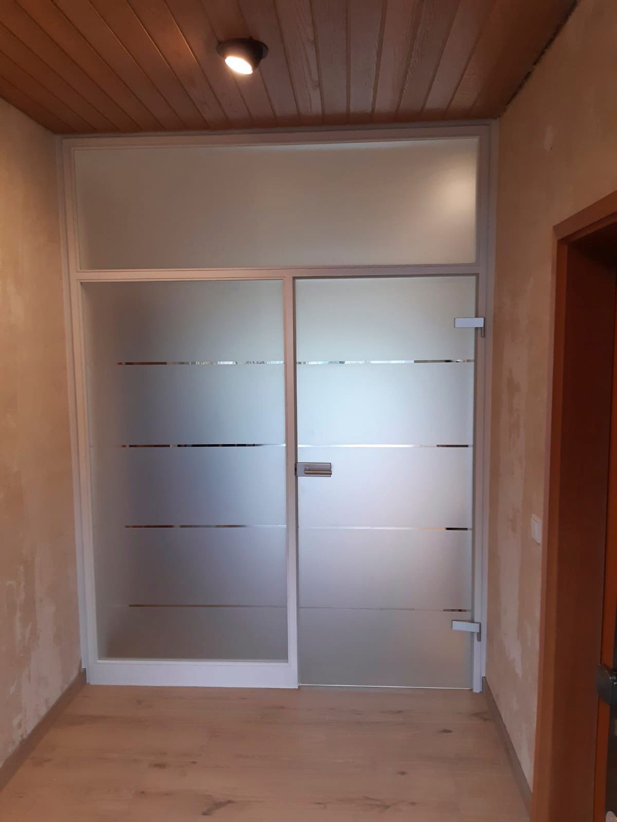 Ein Flur mit Glastür und Holzdecke.