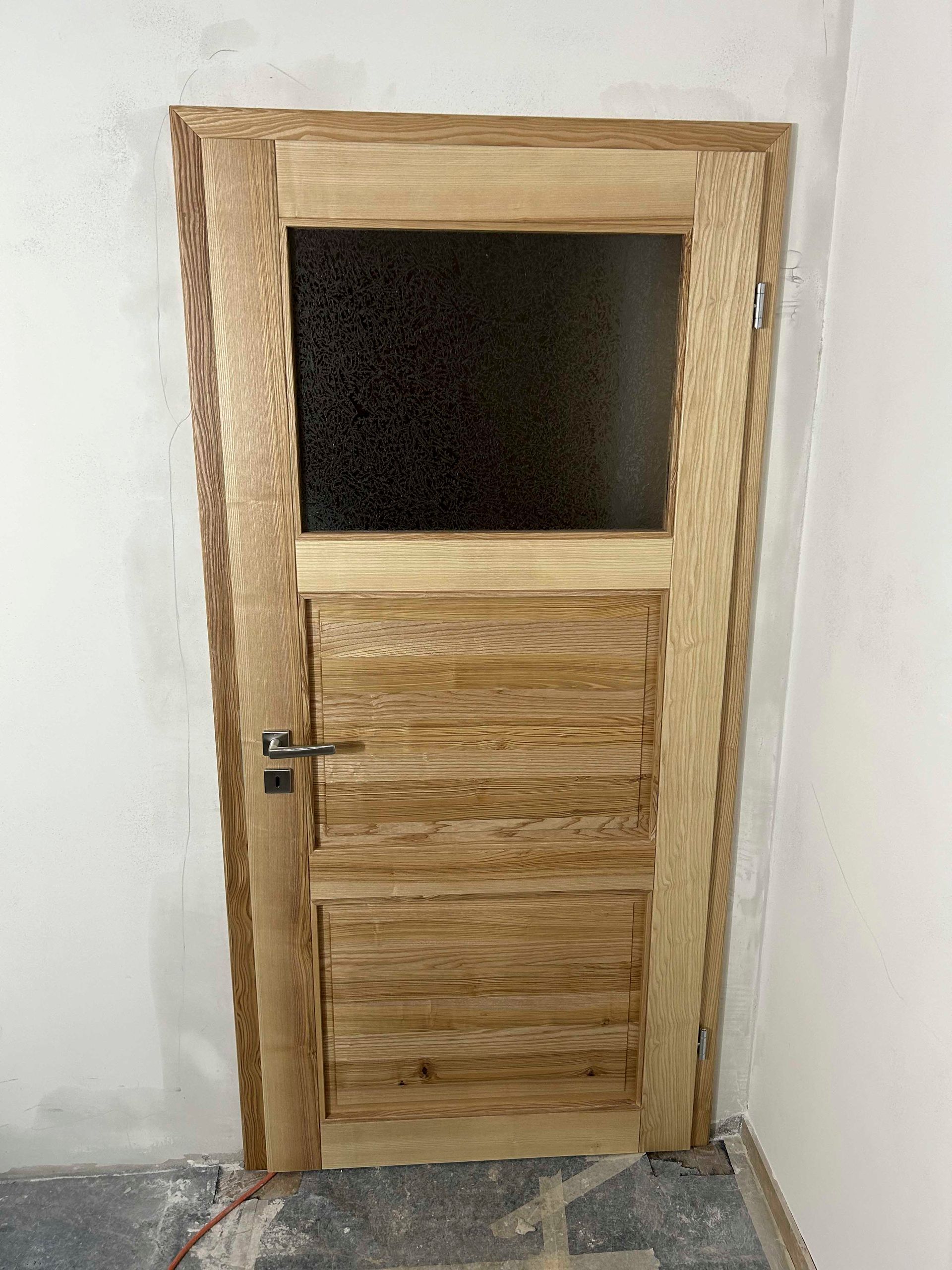 Eine Holztür mit einem Glasfenster in einem Raum.