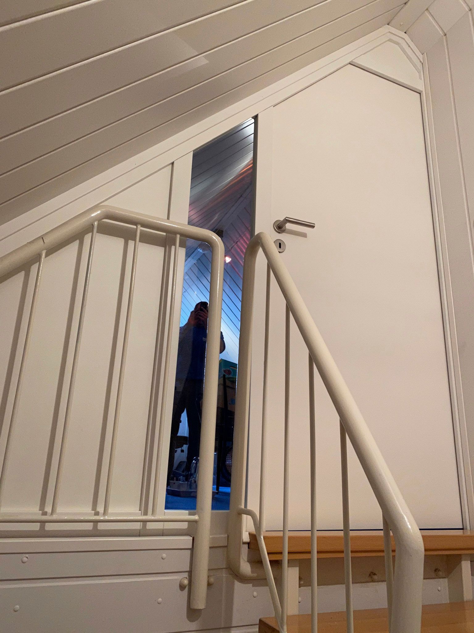 Eine Treppe mit weißem Geländer und weißer Tür