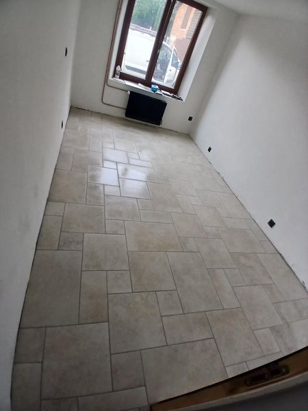 Pose de carrelage terminée dans une pièce avec une fenêtre.
