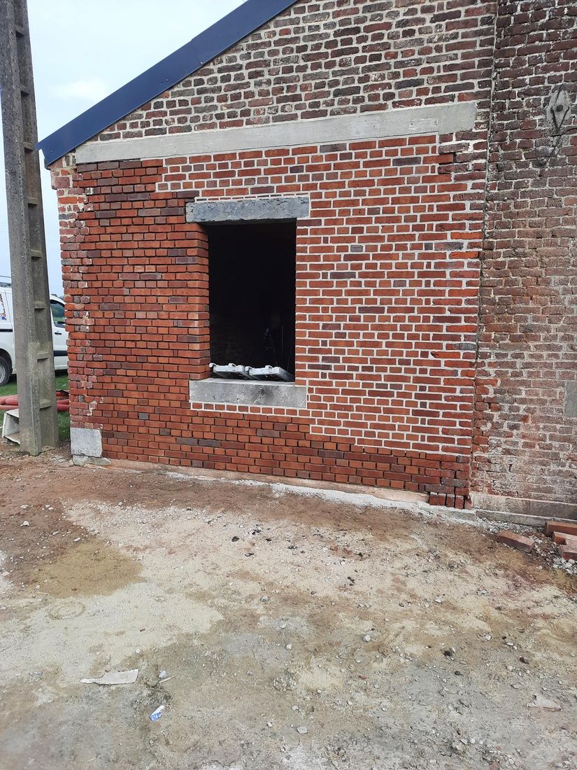 Travaux de rénovation de maçonnerie extérieure avec une façade et une ouverture de fenêtre.