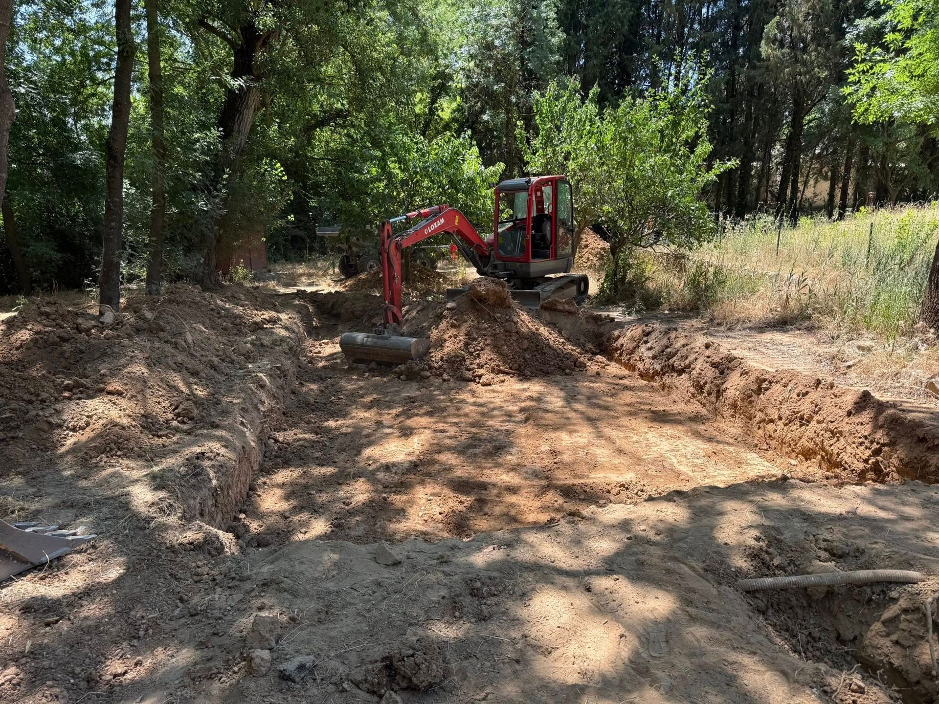 Un chantier de terrassement avec un engin de chantier rouge.