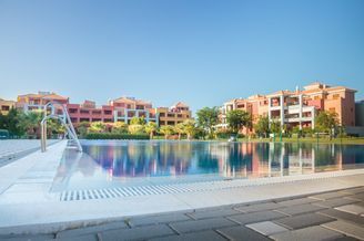 Hay una gran piscina en medio de una zona residencial con edificios al fondo.