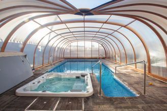 Una gran piscina cubierta con un jacuzzi debajo de ella.