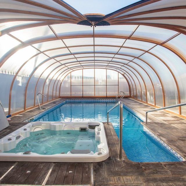 Una gran piscina cubierta con un jacuzzi en el medio