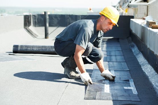 Un hombre que lleva un casco está trabajando en un tejado.
