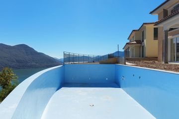 Una piscina vacía con vistas a un lago y a las montañas.