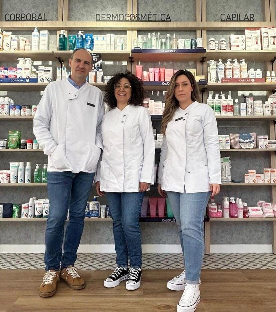 Farmacéutico tomando la presión arterial del paciente en una farmacia, sonriendo, mirándose, bata blanca, fondo claro.