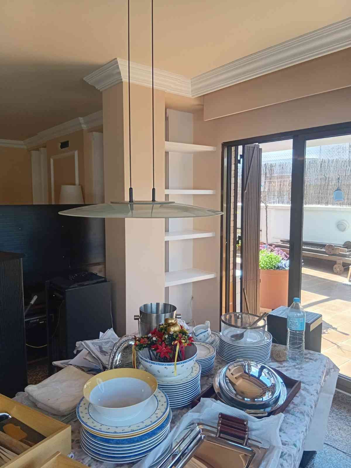 Mesa de comedor puesta con platos y comida junto a una puerta corrediza abierta que da a un patio.