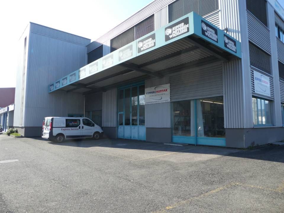 Eingang zum Industriegebäude mit blauer Markise und einem davor geparkten weissen Lieferwagen.