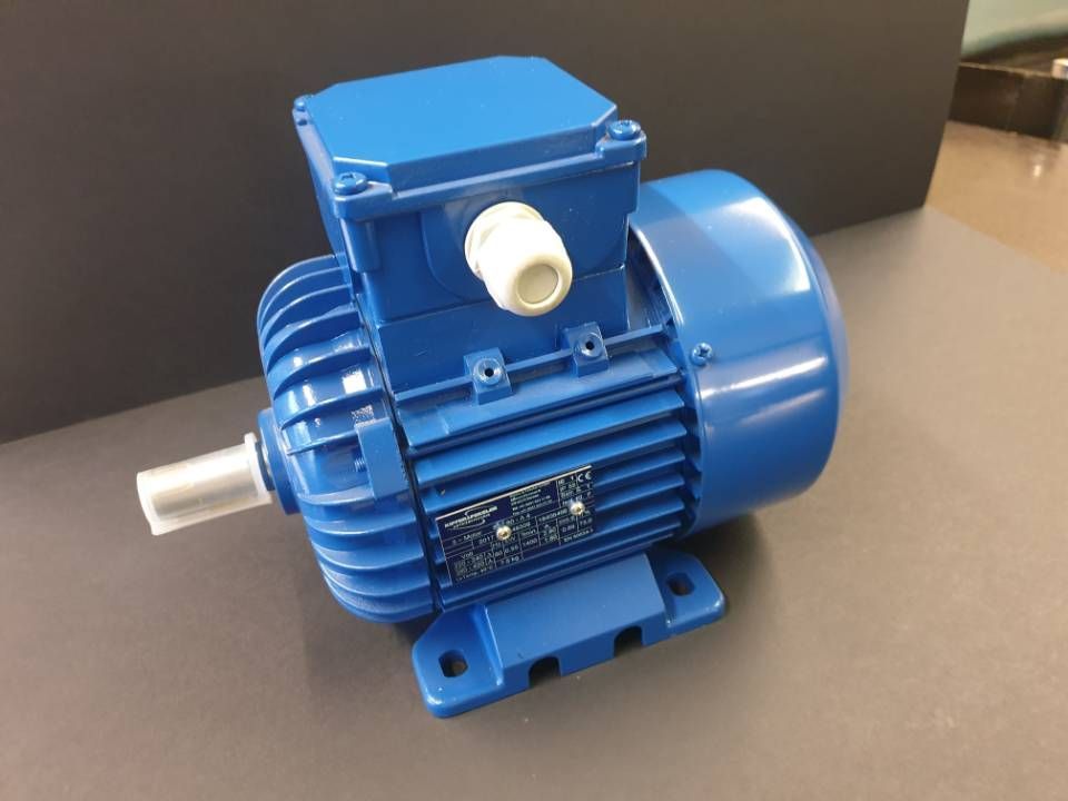 Blauer Elektromotor mit silberner Welle, montiert auf blauem Sockel vor dunklem Hintergrund