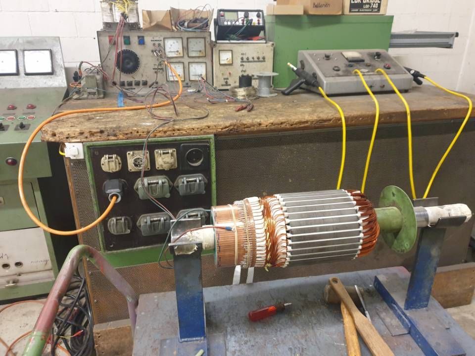 Werkbank mit zerlegtem Elektromotor/Rotor und Prüfgeräten mit angeschlossenen Kabeln.