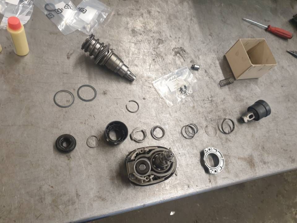 Verstreute mechanische Metallteile und Dichtungen liegen während der Demontage oder Reparatur auf einer Werkbank.