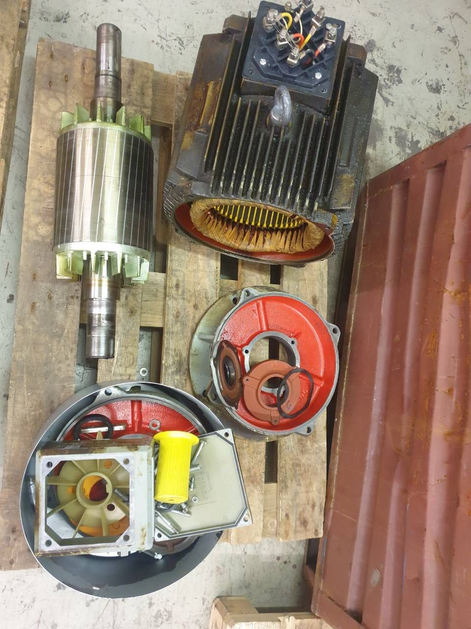Verschiedene Elektromotorteile und Ventilatoren lagen auf Holzpaletten in einem Werkstattbereich.