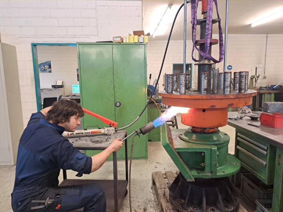 Ein Arbeiter schweisst in einer Werkstatt an einer grossen Industriemaschine Metall, Funken sprühen.