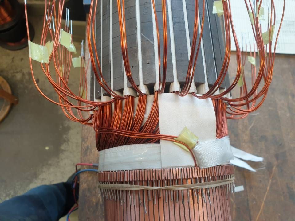 In einer Werkstatt wird Kupferdraht um den Kern eines grossen elektrischen Transformators gewickelt.