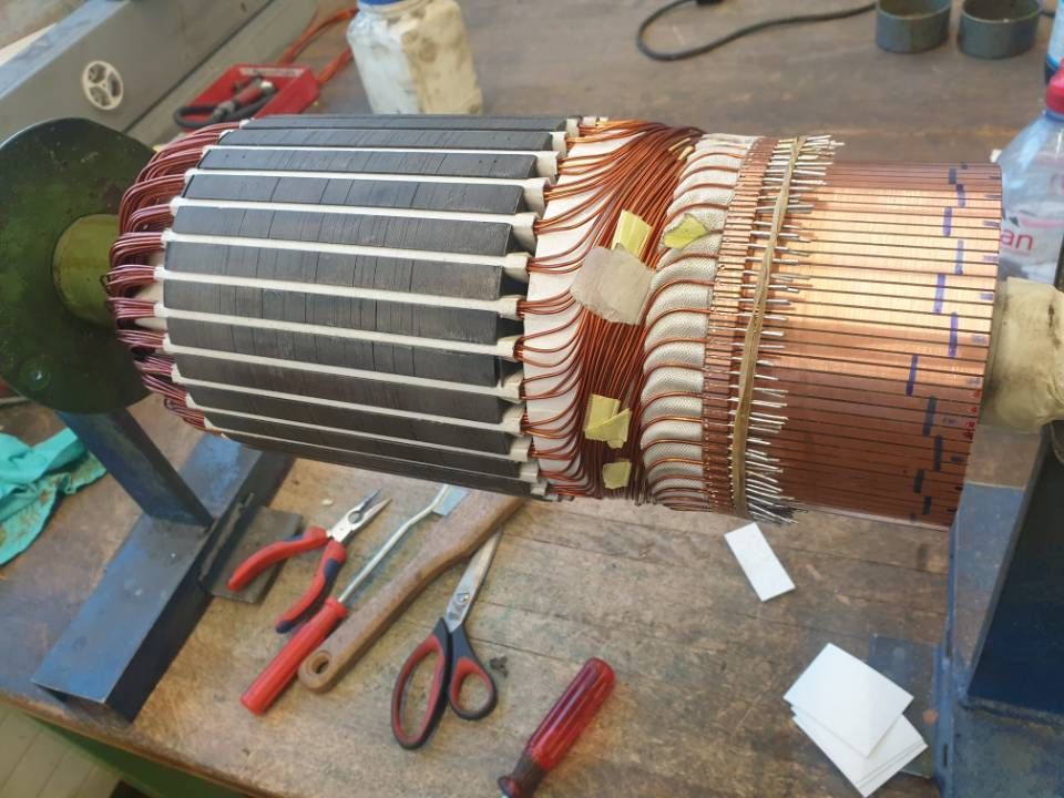 Grosser Elektromotor/Anker auf einer Werkbank, teilweise zerlegt, Werkzeug daneben.