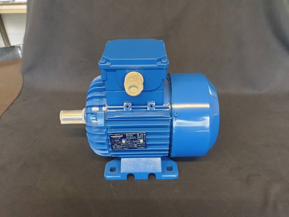 Blauer Elektromotor auf grauem Hintergrund, Seitenansicht mit sichtbaren Montagefüssen und Welle.