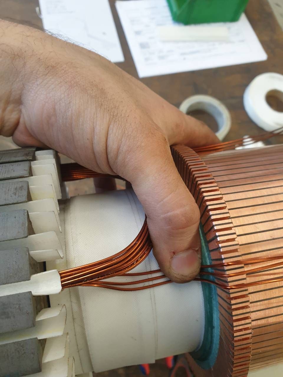 Handwicklung von Kupferdraht um eine weisse Motorspule in einer Werkstatt