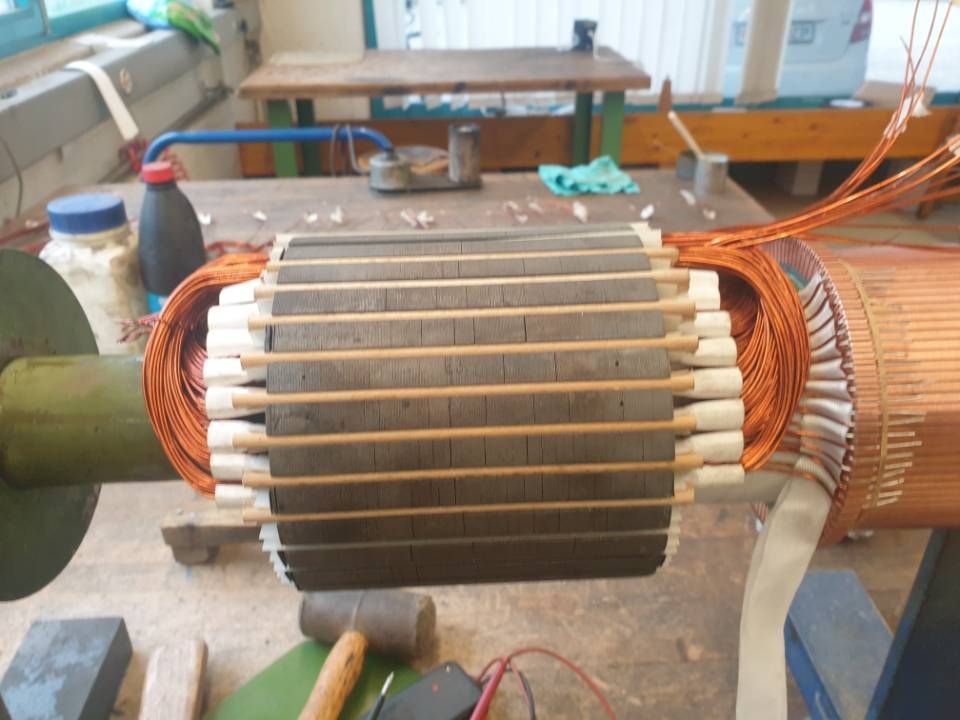 Rotor eines Elektromotors mit Kupferwicklungen und grauen Blechen auf einer Werkstattbank