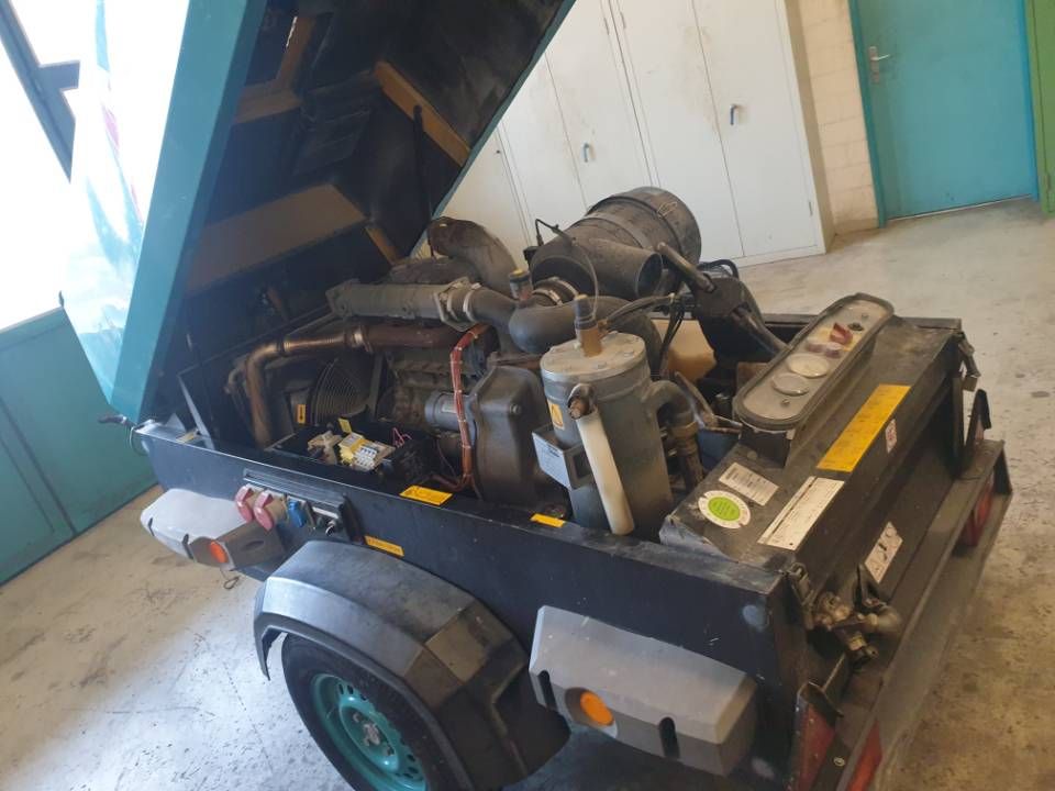 Offener Motorraum eines kleinen Nutzanhängers, der Schläuche, Tanks und Ausrüstung zeigt.
