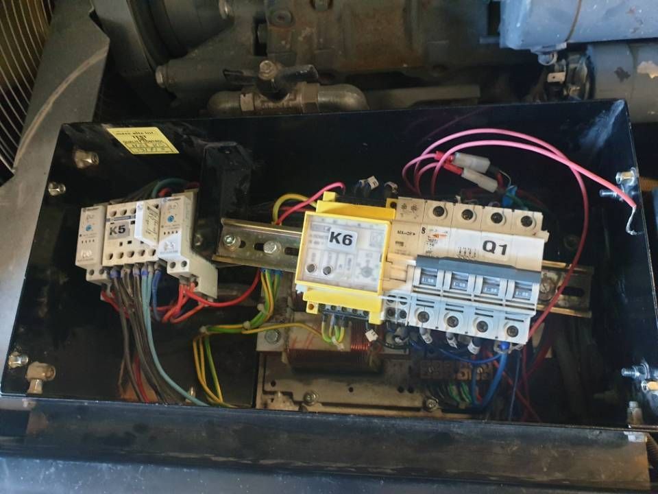 Offener elektrischer Schaltkasten mit Verkabelung, Relais und Leistungsschaltern in einem schwarzen Metallgehäuse