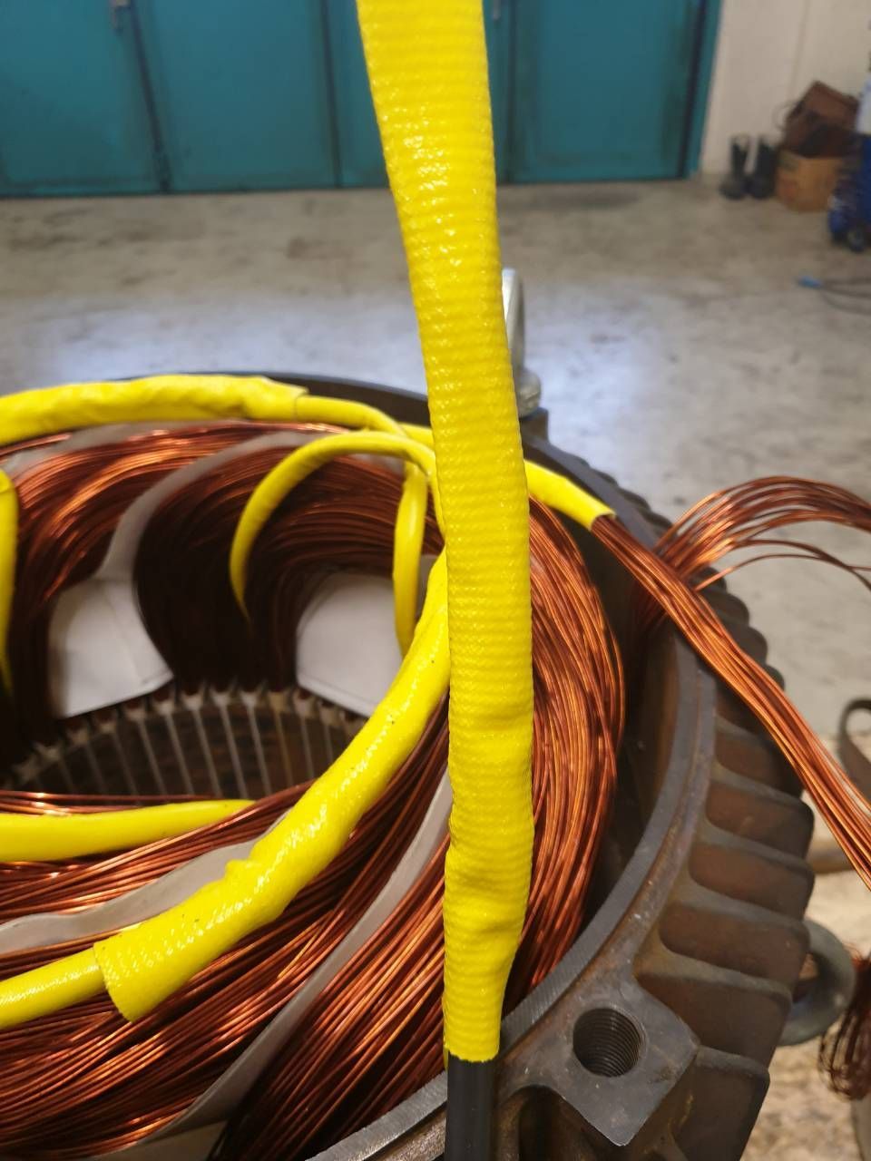 Spulen aus Kupferdraht um einen kreisförmigen Motorstator, mit einem gelben isolierten Kabel in der Mitte.