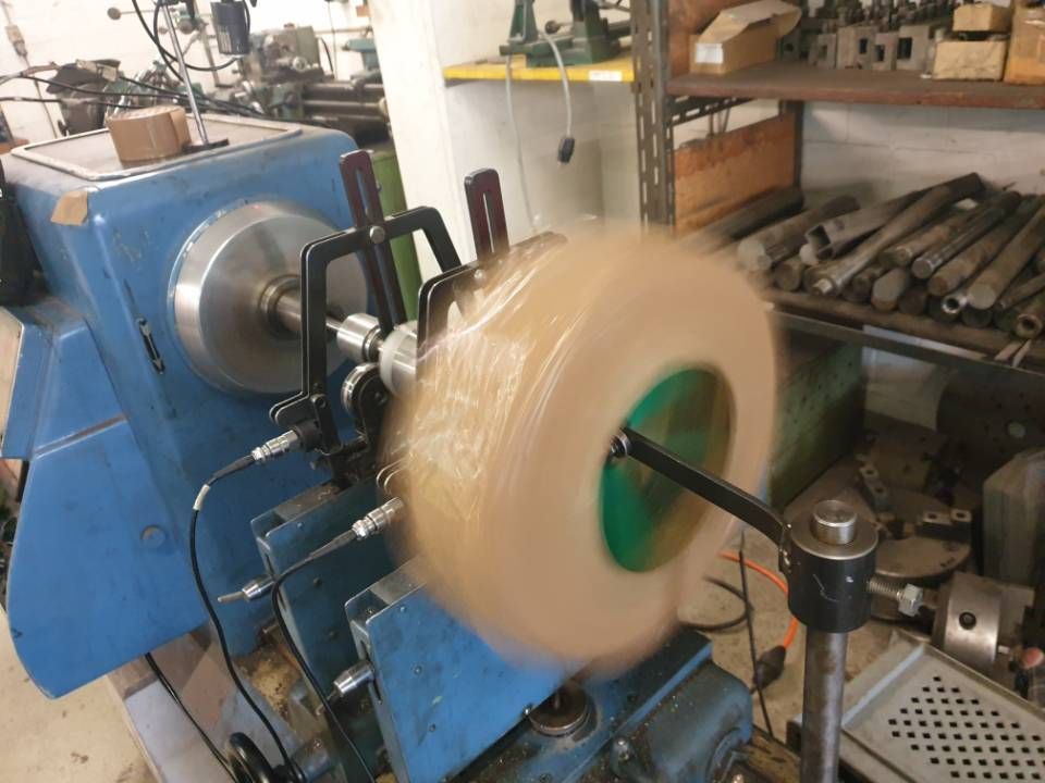 Drehbank mit verschwommenem, sich drehendem Rad in einer Werkstatt, blaue Geräte und Werkzeuge in der Nähe