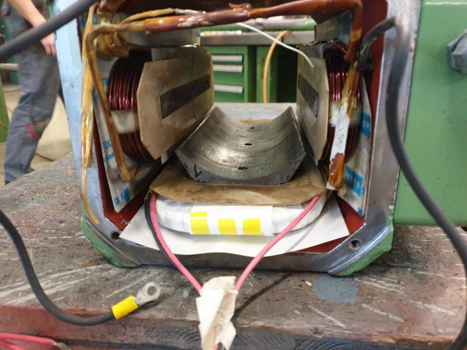 Schnittzeichnung eines beschädigten Elektromotorstators mit freiliegenden Kupferwicklungen auf einer Werkbank